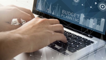 Employee creates budget planning template on laptop.
