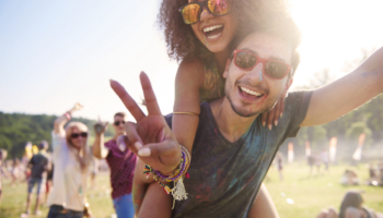 Festival packing list: Man carries woman piggyback at festival