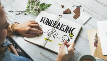Das Wort Fundraising steht in einem Heft mit Strichmännchen