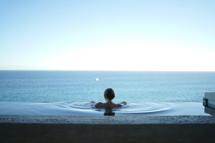 Checkliste Urlaub: Eine Frau genießt den Meerblick in einem Pool