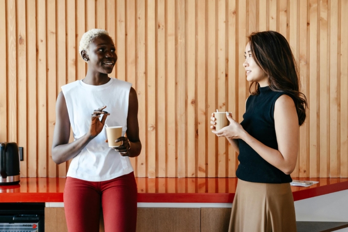 Zwei Kolleginnen sprechen bei einer Tasse Kaffee miteinander