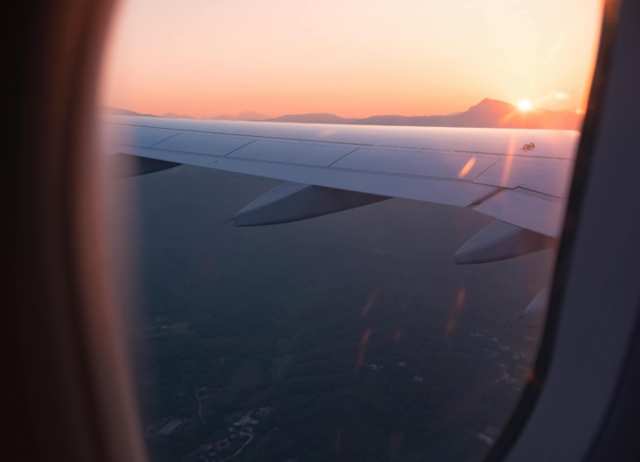 Checkliste Urlaub: Blick auf einen Sonnenuntergang aus einem Flugzeug